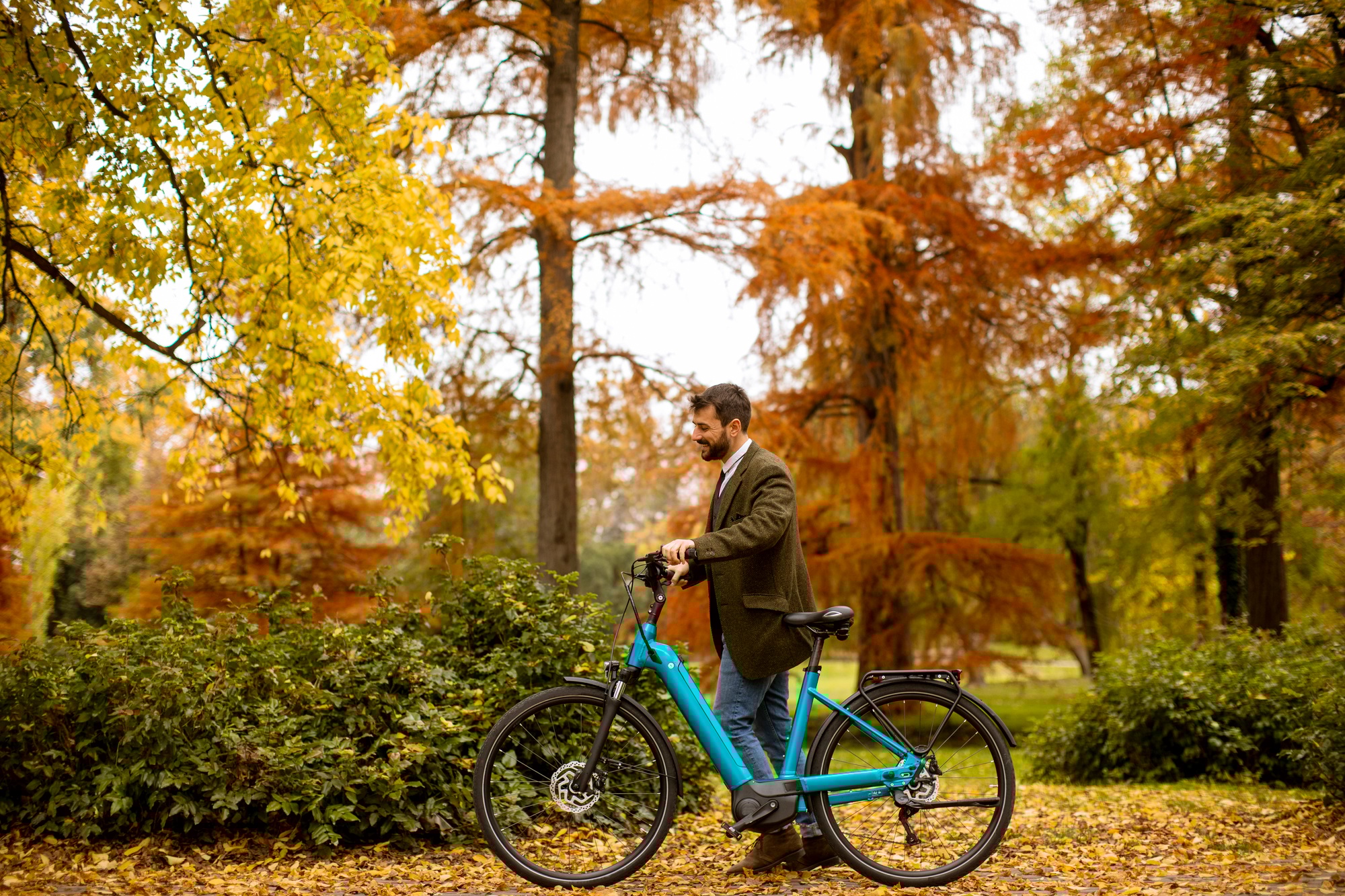 Young man with electric bicycle in the autumn park